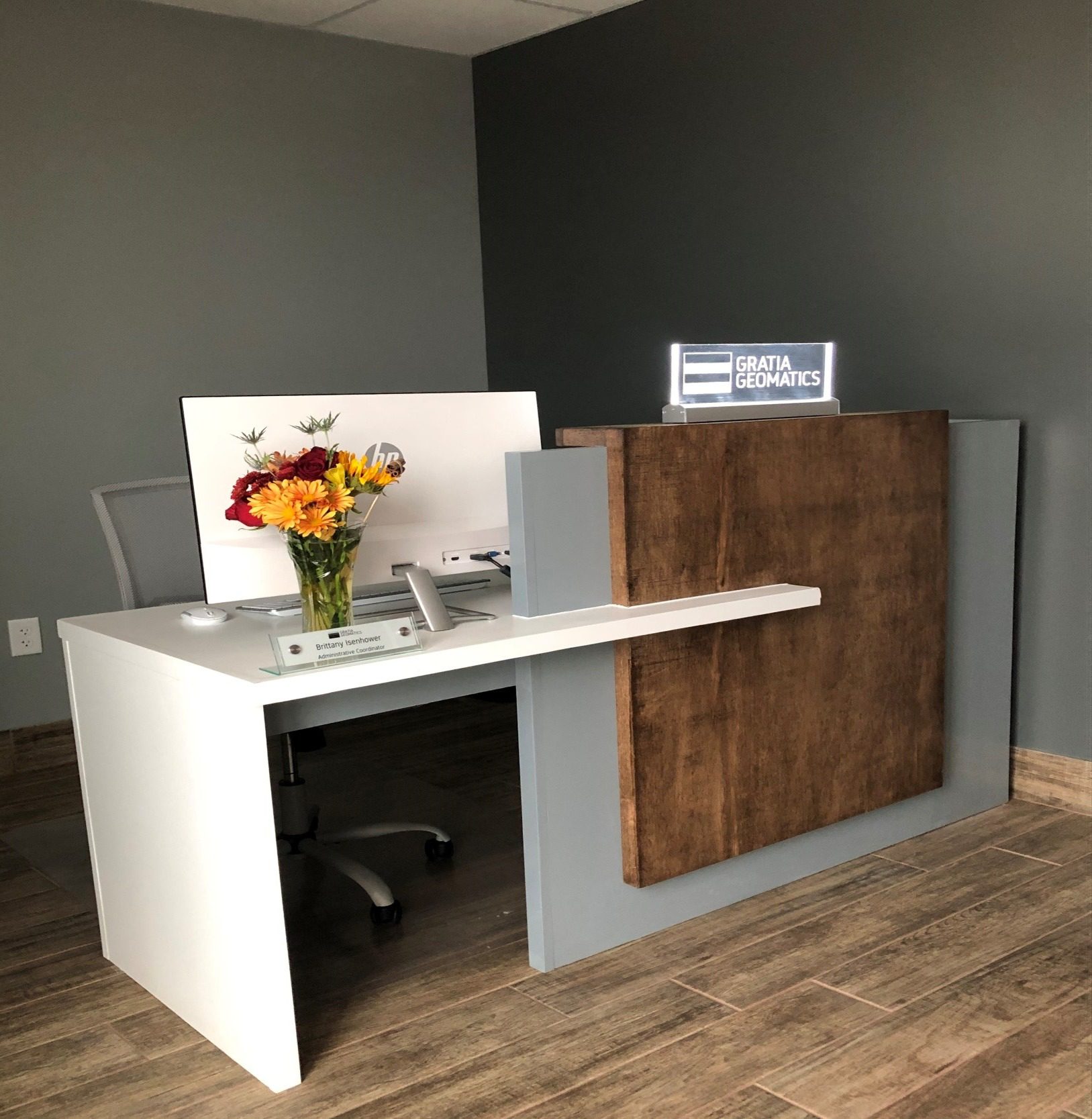 Office reception desk with flowers and sign.